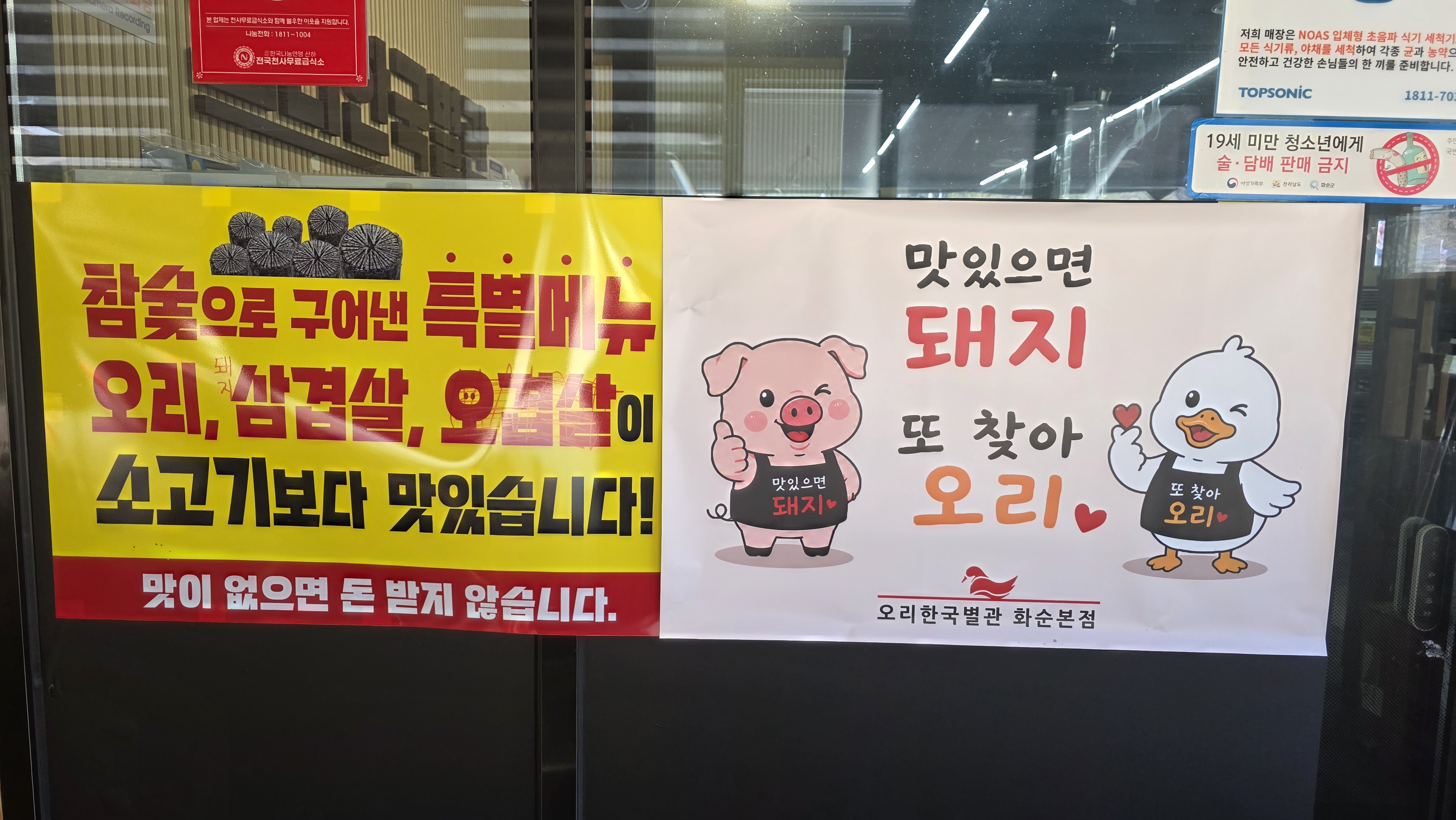 매장 입구에 부착된 참숯 구이 특별메뉴 안내문 및 캐릭터 홍보물